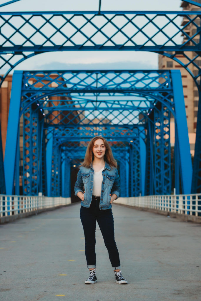 high school senior standing on blue bridge
