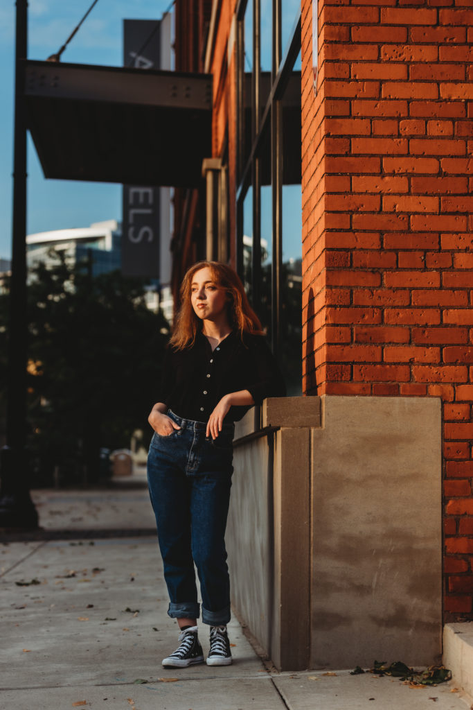 high school senior staring off leaning against building