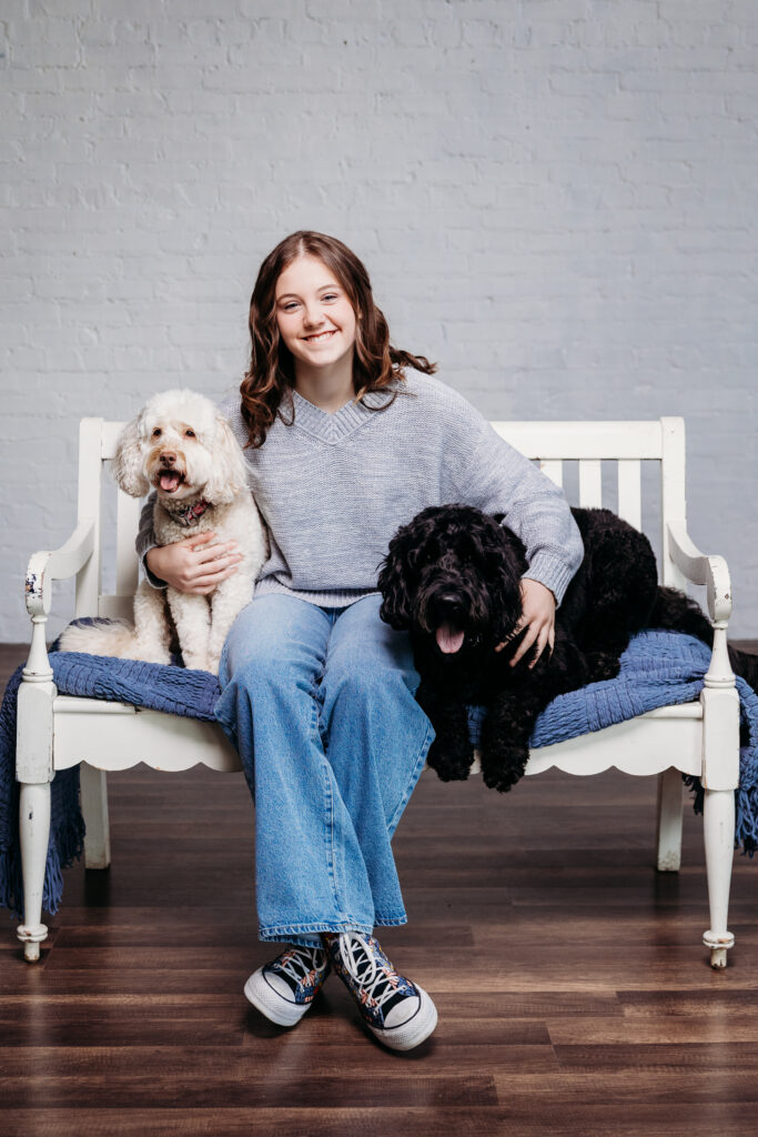 teen girl sitting on bench with her dogs