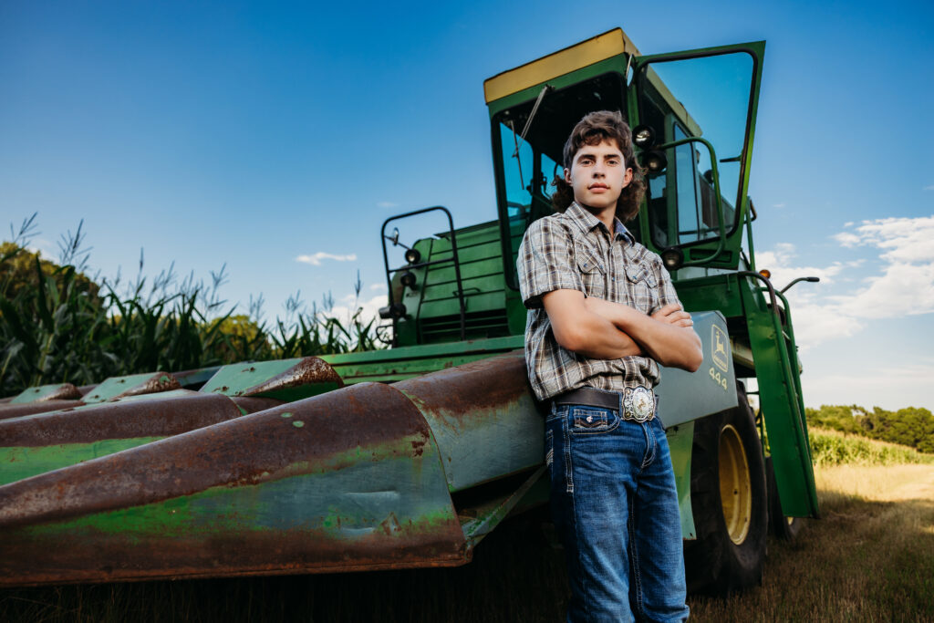 senior boy posing with combine tractor